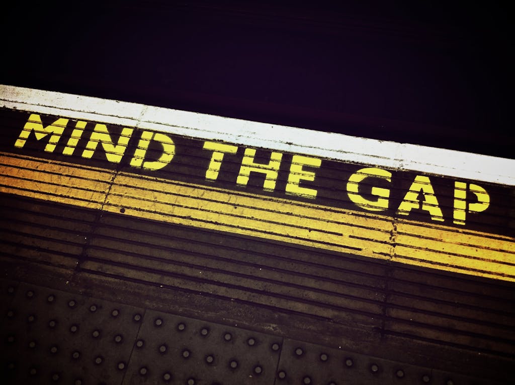 Bold 'Mind the Gap' text on a subway platform, emphasizing passenger safety.